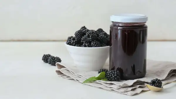 Frische Brombeeren und ein Glas selbstgemachtes Brombeergelee. So lässt sich das Gelee noch verfeinern.