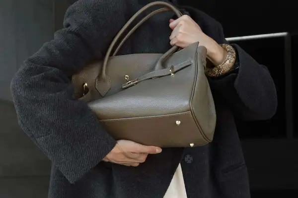 Elegancka, szara torebka z wysokiej jakości skóry, idealna dla miłośniczek luksusowych marki torebek. Złote okucia dodają jej blasku.