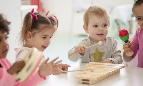 Kinder unter 3 Jahren musizieren fröhlich mit Xylophon und Maracas.