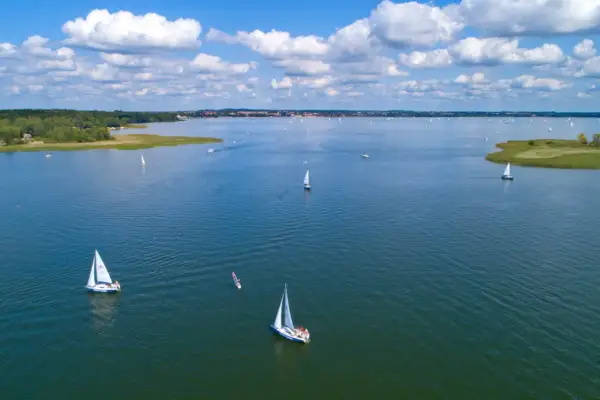 Segelboote auf dem Wasser in Masuren, Polen. Ein sonniger Tag mit Wolken, ideal zum Segeln.