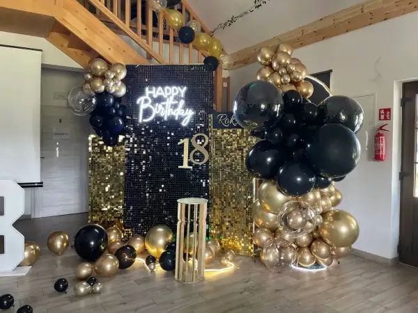 Błyszcząca ścianka z cekinów, neon "Happy Birthday", balony czarne i złote, cyfra 18.