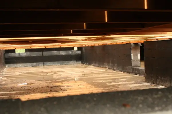 Fundament pod słupy drewniane, z bloczków betonowych, z wilgotną ziemią i drewnianym stropem.