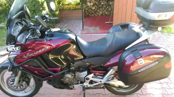 Czerwony motocykl Honda Varadero 1000 z kuframi, zaparkowany na podjeździe.