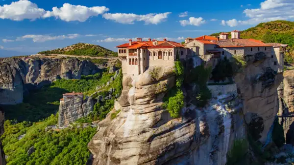 Meteora Kloster, ein atemberaubendes Bauwerk auf Felsen, thront majestätisch über einer grünen Schlucht.