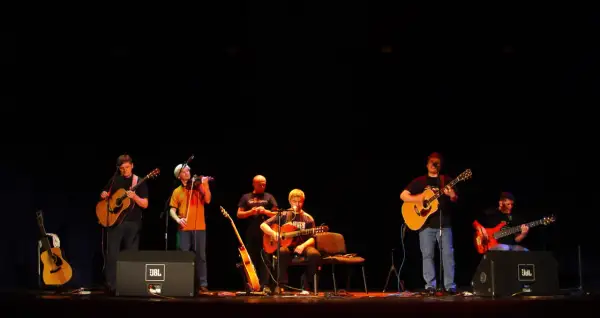 Zespół gra na gitarach i skrzypcach. W tle słychać **stare dobre małżeństwo utwory**.