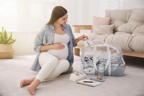 Przyszła mama przygotowuje torbę do porodu, układając maleńkie buciki na wierzchu.