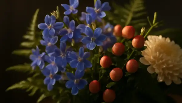 En bukett med små, blå lobelia-blommor, röda bär och en krämvit blomma.