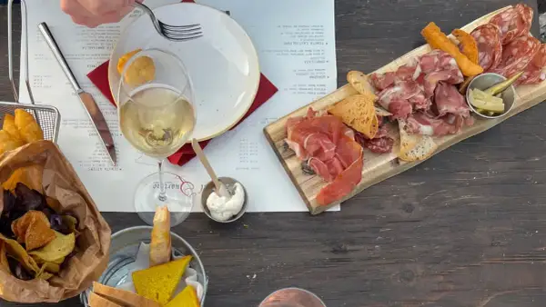 Assiette de charcuterie et de fromage, vin blanc, chips et pain, dans un vignoble de la province de Grosseto.