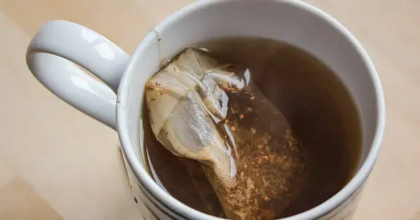 Kubek z czarną herbatą i torebką. Choć ma wiele zalet, czarna herbata właściwości negatywne też posiada, np. może powodować bezsenność.