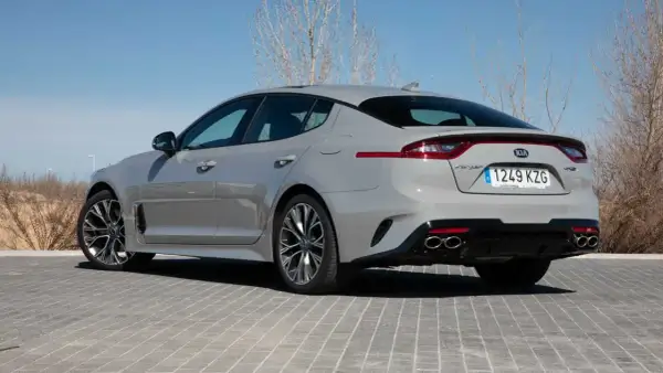 Kia Stinger GT CV gris, visto desde atrás, aparcado sobre adoquines grises.