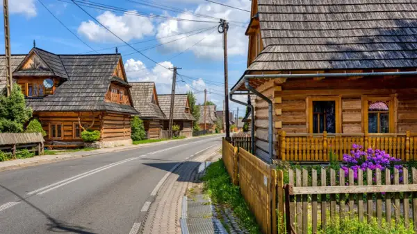 Drewniane domy w stylu zakopiańskim wzdłuż drogi. Wiele atrakcji w okolicy Chochołowa czeka na odkrycie.