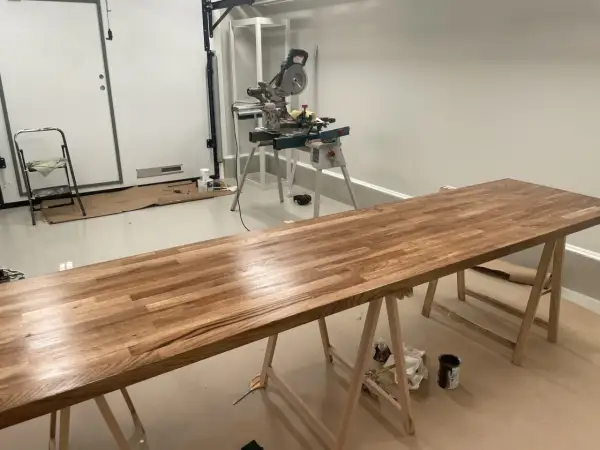 Långt ekbord på sågbockar, redo att behandla ekbordet. Kap- och geringssåg i bakgrunden.