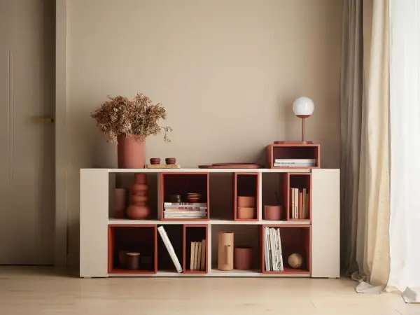 Nowoczesna biblioteczka z elementami w kolorze terakota, wypełniona książkami i dekoracjami.