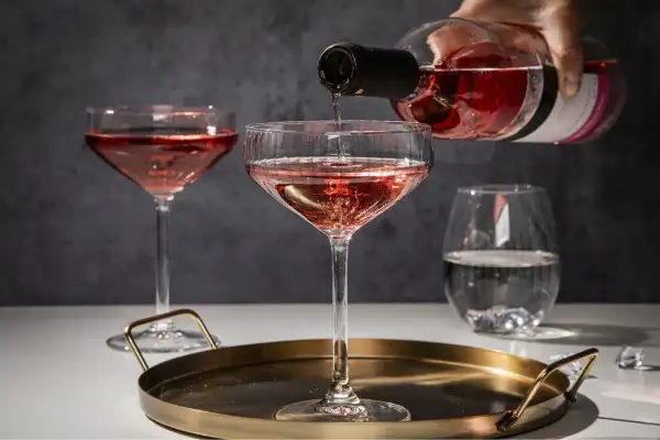 Różowe wino nalewane do eleganckich kieliszków. Idealny wieczór z przyjaciółmi przy lampce orzeźwiającego różowego wina.