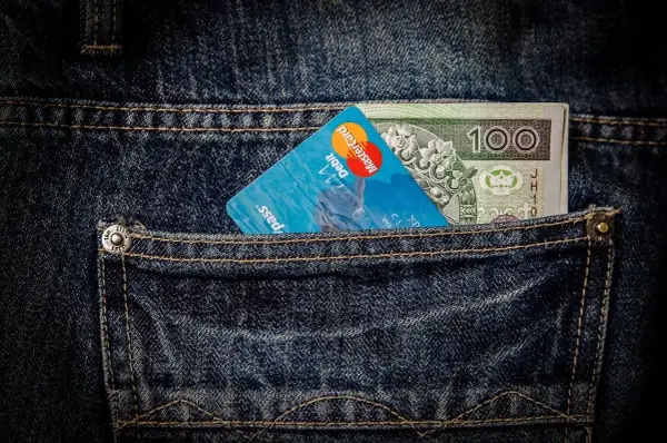 Karta płatnicza i banknot 100 zł w tylnej kieszeni dżinsów. To nowoczesna waluta, gotowa na podróż na Bali.