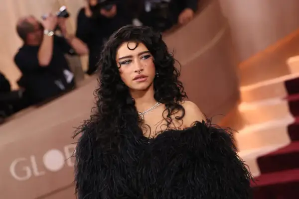 Odessa A'zion, con su cabello rizado y oscuro, luce un elegante vestido negro de plumas y un collar de diamantes.