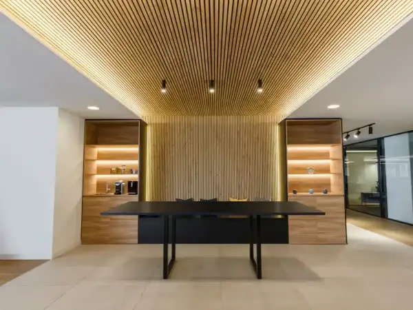 Modern office interior with a wall covered in vertical wood slats, demonstrating como poner listones de madera en la pared.