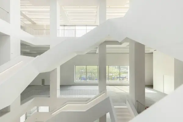 Wnętrze nowego muzeum sztuki nowoczesnej w Warszawie. Białe, geometryczne schody i przestrzenie tworzą nowoczesną architekturę.