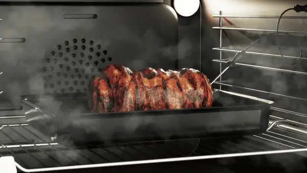 Soczysta pieczeń w piekarniku, wykorzystująca funkcję grill, paruje i apetycznie się rumieni.