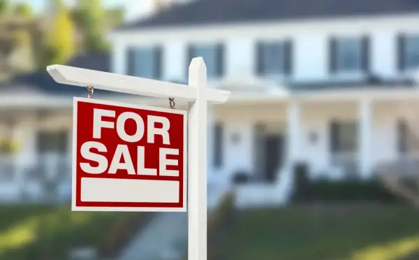 Cartello "For Sale" davanti a una casa. Si può vendere un immobile senza successione, una nuova opportunità per chi cerca casa.