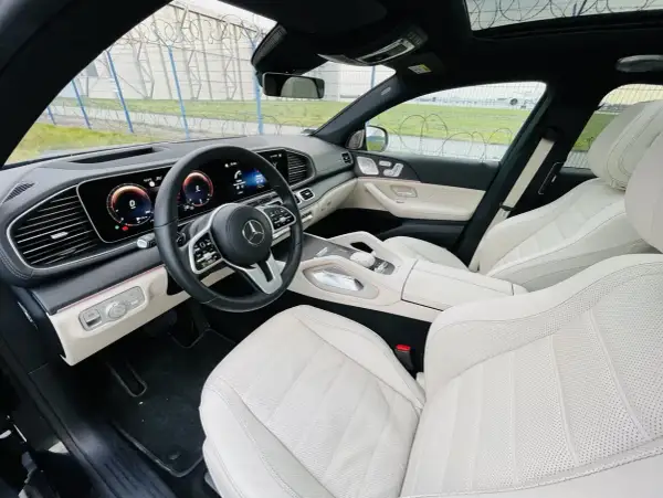 Wnętrze luksusowego Mercedesa GLE 400d z jasną, skórzaną tapicerką i nowoczesnym kokpitem.