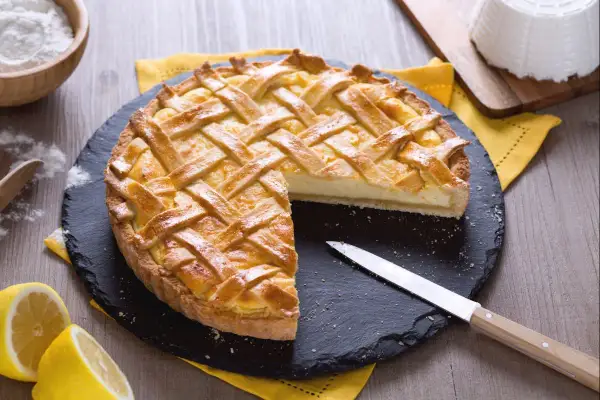 Délicieux dessert ricotta citron, une tarte dorée à la garniture crémeuse, prête à être dégustée.