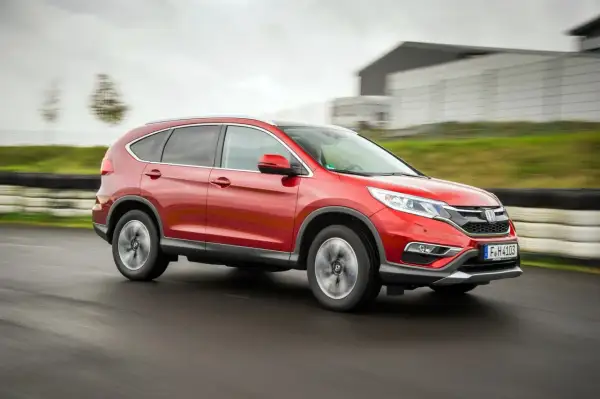 Czerwony Honda CR-V 4. generacji pędzi po torze wyścigowym, ukazując swoją dynamiczną sylwetkę.