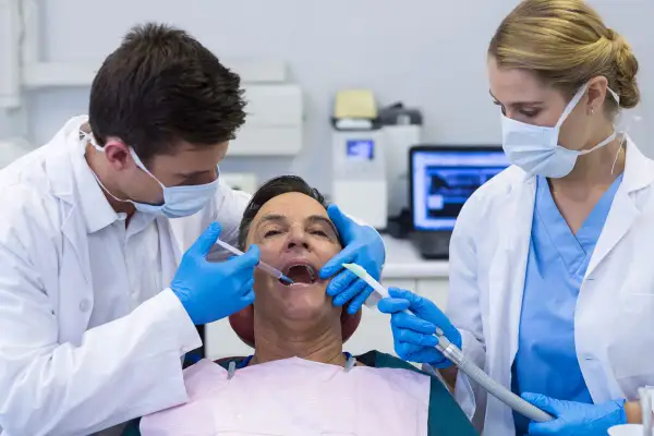 Dentysta podaje znieczulenie, a asystentka przygotowuje się do zabiegu. Ciekawe, ile trzyma znieczulenie u dentysty, by zabieg był bezbolesny.