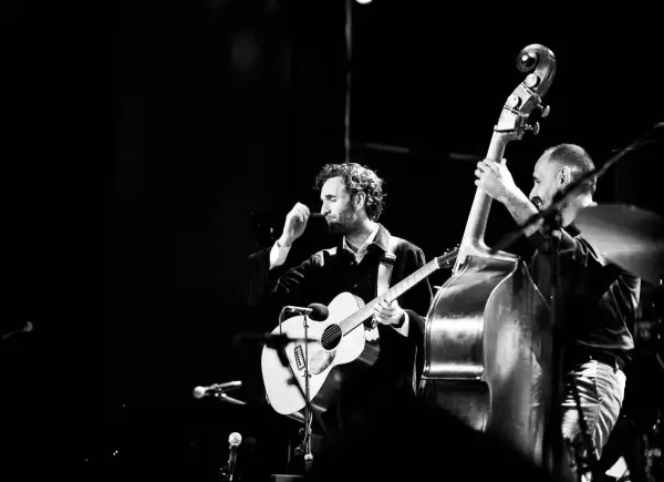 Julian Lage gra na gitarze akustycznej obok kontrabasisty na scenie.