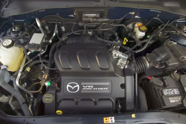 Silnik V6 DOHC 24-zaworowy w Mazda Tribute. Widoczny zbiornik płynu chłodniczego, akumulator i elementy układu dolotowego.