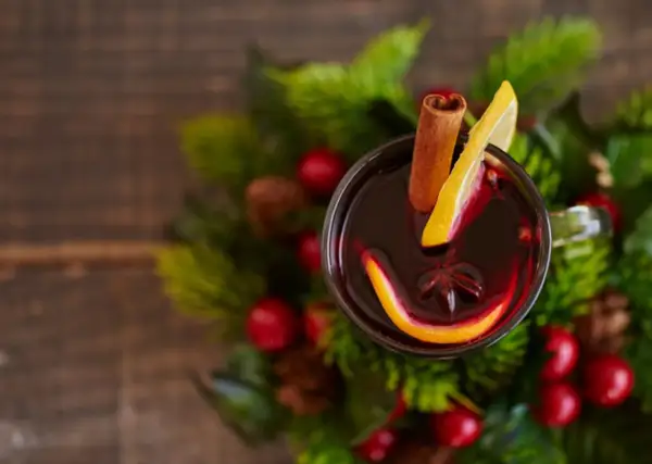 Glogg przepis: aromatyczny grzaniec z pomarańczą, cytryną i cynamonem, otoczony świątecznymi gałązkami.