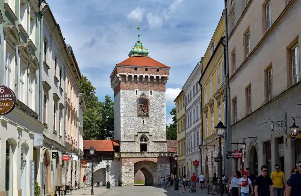 Brama Floriańska w Krakowie, majestatyczna wieża z czerwoną dachówką i kamienną fasadą, wita spacerowiczów.