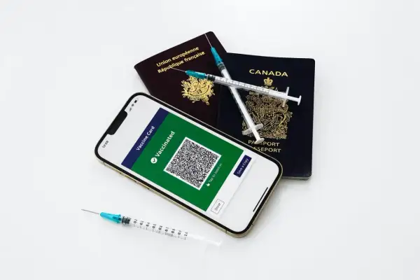 Gotowi na podróż? Paszporty, telefon z potwierdzeniem szczepień i strzykawki symbolizują przygotowania do wyjazdu.