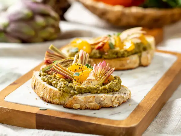 Deliziosi crostini con paté di carciofi, spicchi d'arancia e finocchietti croccanti su pane integrale tostato.