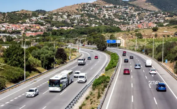 Voiture sur autoroute en Espagne, respectant la limitation vitesse espagne. Paysage vallonné avec des maisons en arrière-plan.