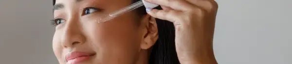 Frau trägt ein Serum mit Linolsäure auf, um ihre Haut zu pflegen.