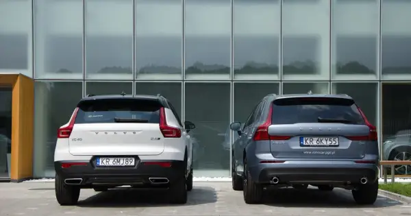 Dwa SUV-y Volvo: białe XC40 i szare XC60, stoją przed nowoczesnym budynkiem. Porównanie ich wymiarów jest łatwe.