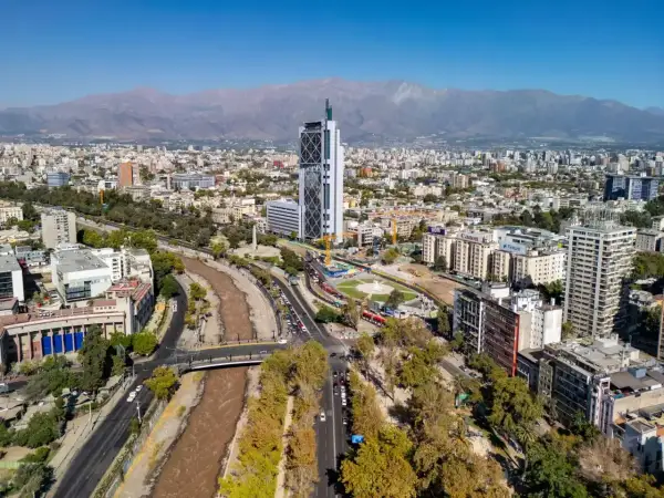 Widok na nowoczesną architekturę i rzekę w Santiago, stolicy Chile, z górami w tle.
