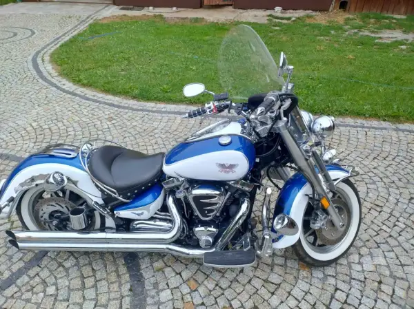 Błękitno-biały Yamaha Road Star 1700 lśni chromem na brukowanym podjeździe, gotowy na przygodę.
