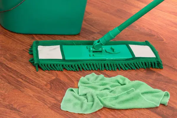 Mocio verde e secchio su pavimento in legno, pronti per pulire con ammoniaca per pavimenti.