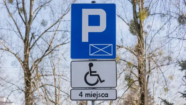Znak P z kopertą i symbolem wózka inwalidzkiego, informujący o 4 miejscach parkingowych dla niepełnosprawnych.