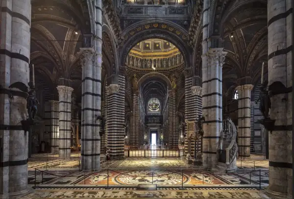 Interno del Duomo di Siena, con il suo magnifico pavimento intarsiato e le colonne a strisce bianche e nere che conducono verso l'altare.