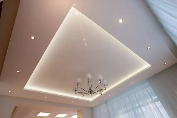 Nowoczesne aranżacje sufitów podwieszanych z subtelnym podświetleniem LED i eleganckim żyrandolem. Wzory tworzą przestrzeń.