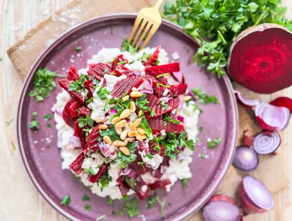Rote Bete Salat nach Omas Art: ein cremiger Salat mit Rote Bete, Zwiebeln, Pinienkernen und frischer Petersilie, serviert auf einem lila Teller.