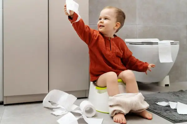 Bambino di 4 anni sul vasino, con rotoli di carta igienica sparsi. Un piccolo disastro, ma un grande passo verso l'indipendenza!
