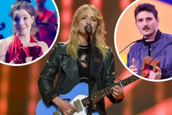 Trzy osoby na scenie: kobieta gra na gitarze, kobieta w czerwieni trzyma nagrodę, mężczyzna z wąsami trzyma nagrodę.