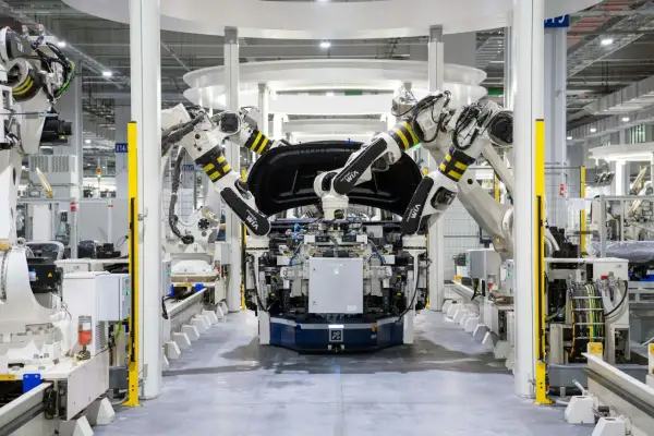 Roboterarme montieren ein Autoteil in einer Fabrik. Bosch KI steuert die präzisen Bewegungen.