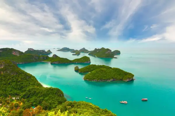 Grüne Inseln im türkisfarbenen Meer, ein Paradies für die beste Reisezeit Asien. Boote gleiten auf dem Wasser.