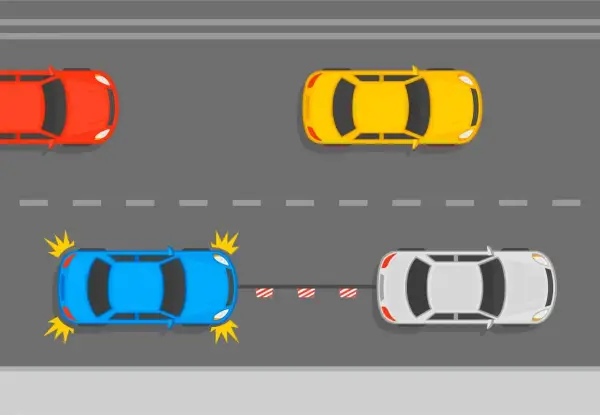 Niebieski samochód z uszkodzeniami jest holowany przez biały. Czy można holować auto bez przeglądu? Czerwony i żółty samochód jadą dalej.