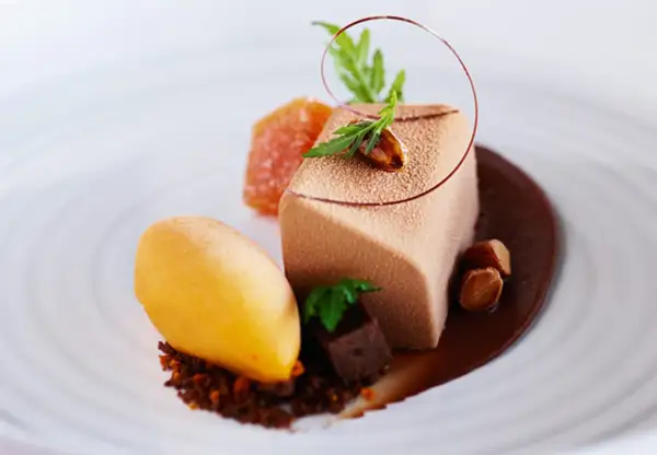 En elegant choklad havtorn dessert med en mousse, sorbet, kanderade nötter och en chokladsås.